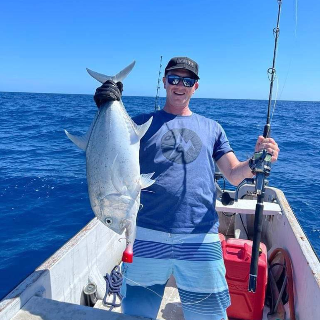 Guy posing with fish catch from popper fishing on Big Blue Fiji fishing charter